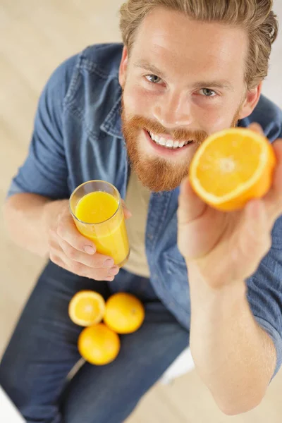 Νεαρός Άνδρας Που Κρατάει Πορτοκάλι Και Ένα Ποτήρι Χυμό Πορτοκάλι — Φωτογραφία Αρχείου