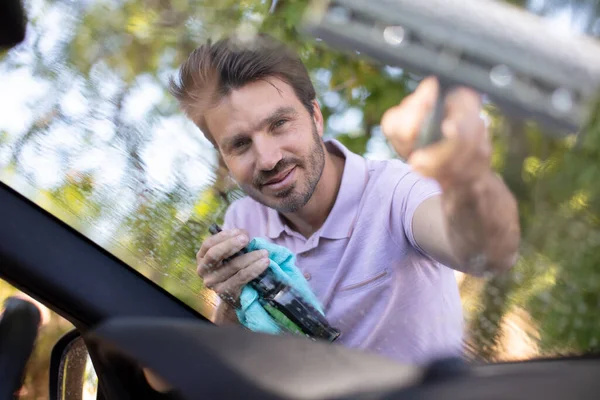 男人用刷子刷洗汽车的挡风玻璃 — 图库照片