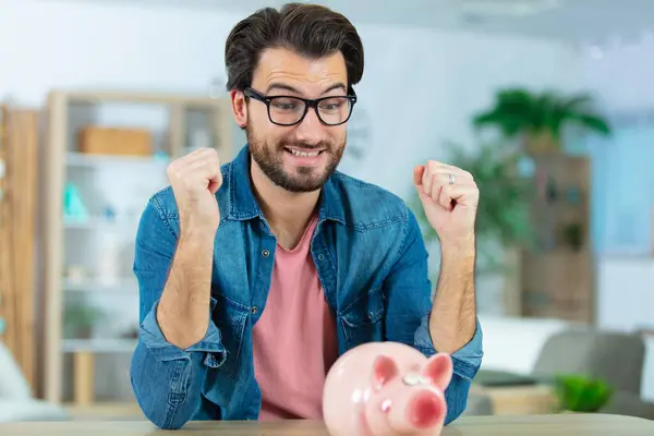 Glücklicher Junger Mann Legt Geld Sparschwein — Stockfoto