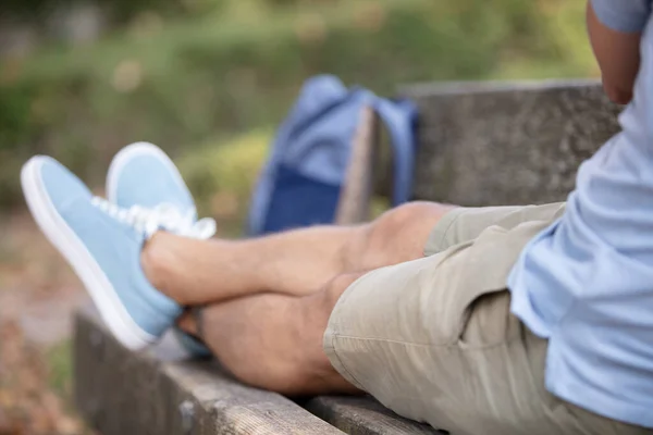 公園のベンチに寝そべっている男の足は — ストック写真