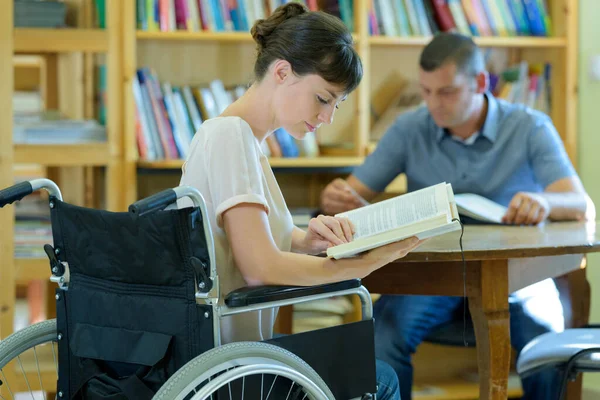 Kütüphanede Tekerlekli Sandalyede Kitap Okuyan Engelli Bir Kadın — Stok fotoğraf