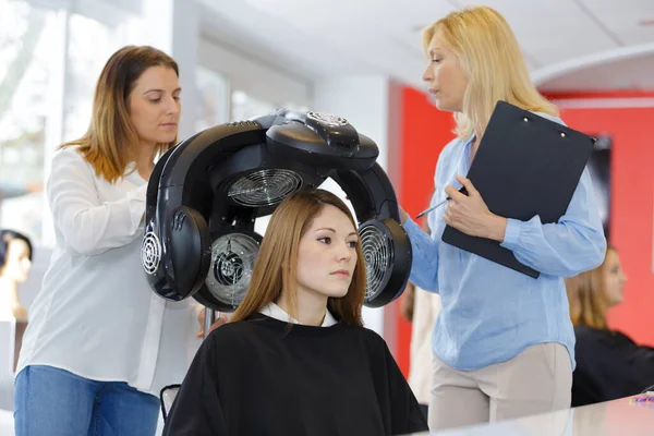 trainee hairdresser using electrical device around clients head