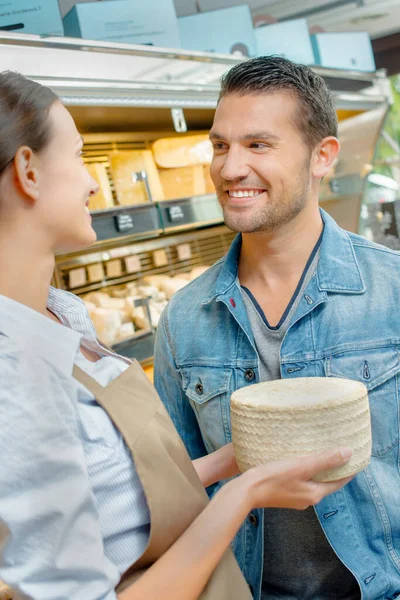 Female Shop Worker Showing Large Cheese Customer Royalty Free Stock Photos