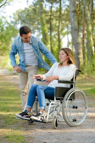 坐在轮椅上的年轻夫妇在乡间散步 — 图库照片