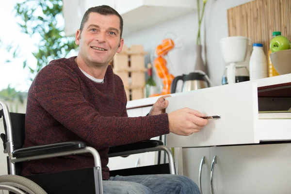 Szczęśliwy Niepełnosprawnych Człowiek Siedzi Wózku Inwalidzkim Otwarta Szuflada Kuchni — Zdjęcie stockowe