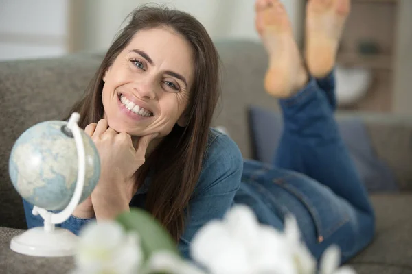 Glückliche Frau Lächelnd Mit Globus Auf Sofa Sitzend — Stockfoto