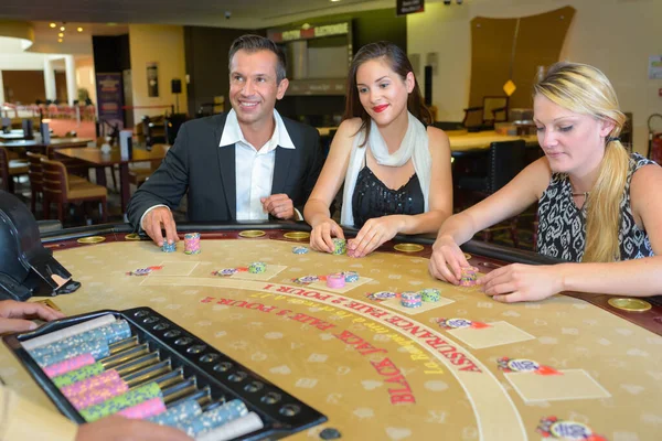 カジノで3人のエレガントな大人がギャンブルをし — ストック写真