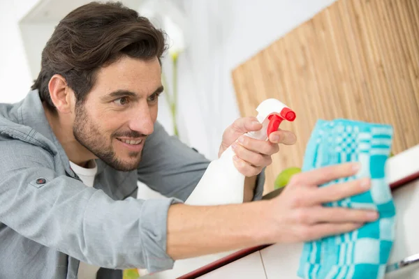 男子喷洒清洁剂以清洁厨房的工作台 — 图库照片