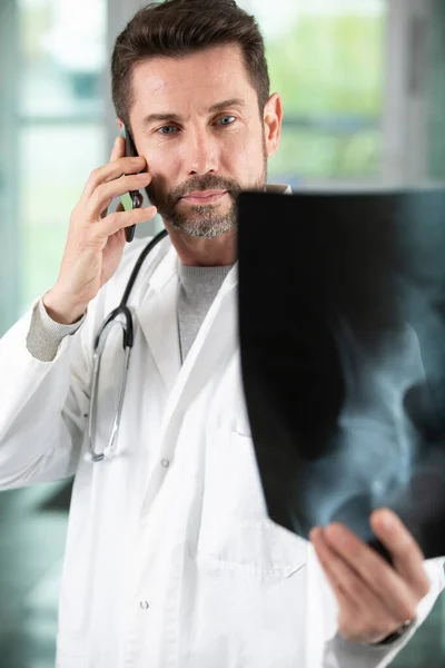 Arzt Krankenhaus Schaut Sich Röntgenbild Während Telefoniert — Stockfoto