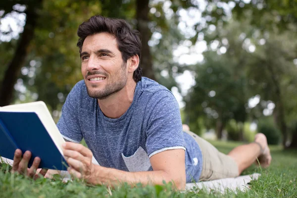 Szczęśliwy Człowiek Leżący Trawie Czytający Książkę — Zdjęcie stockowe