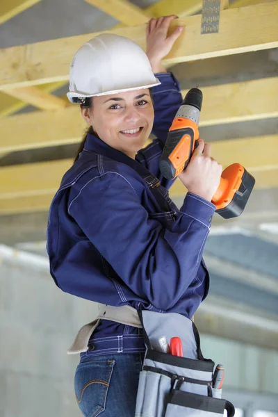 使用钻头建造天花板的年轻女建筑工人 — 图库照片