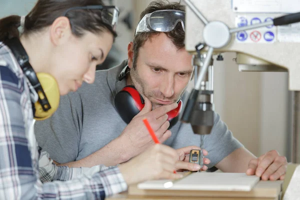 Man Supervising Young Woman Using Bench Drill — Stock Photo, Image