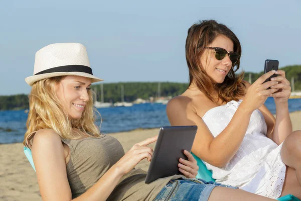 Две Женщины Читают Книгу Электронную Книгу Берегу Моря — стоковое фото