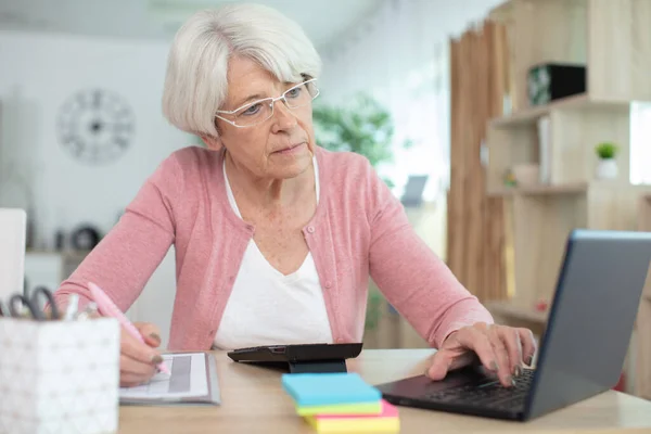Ηλικιωμένη Γυναίκα Που Χρησιμοποιεί Φορητό Υπολογιστή Και Κρατά Σημειώσεις — Φωτογραφία Αρχείου
