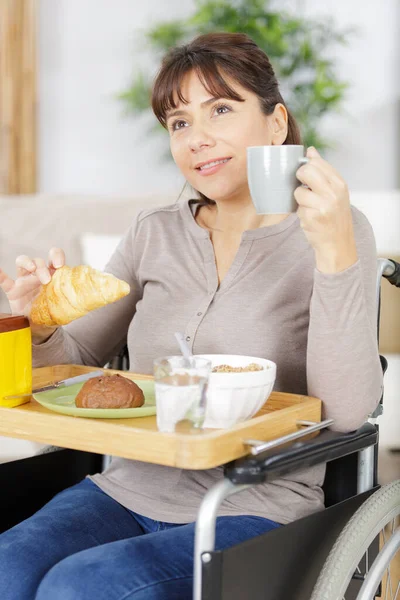家で朝食を楽しむ車椅子の障害者の女性 — ストック写真