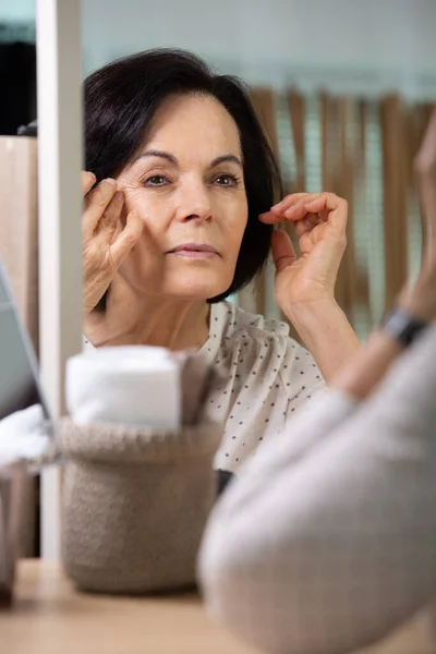 Senior Kvinna Röra Hennes Mjuka Ansikte Hud Tittar Spegeln — Stockfoto