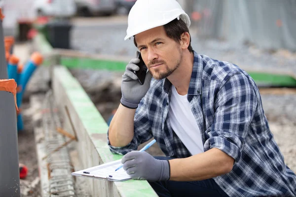 Joven Constructor Hablando Teléfono Móvil Sitio Construcción — Foto de Stock