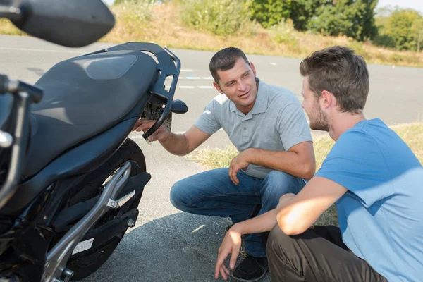 Dva Muži Přikrčení Aby Podívali Zadní Stranu Zaparkované Motocyklu — Stock fotografie