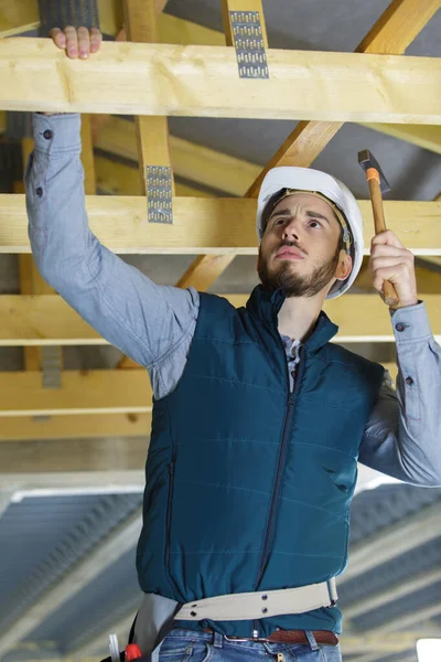 木製の梁にハンマーを使う若い男性建築家 — ストック写真