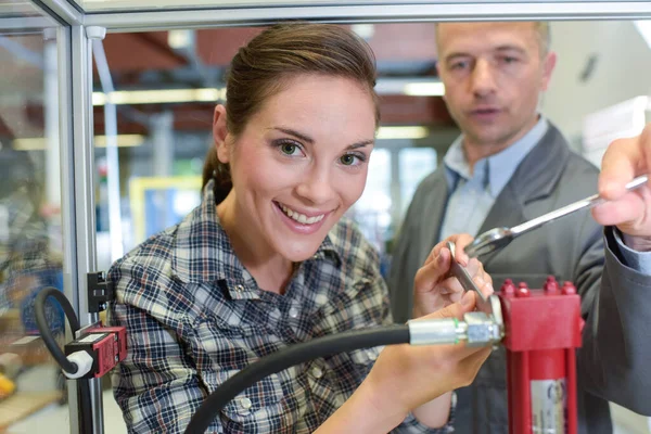 若い女性が工房で機械を修理し — ストック写真