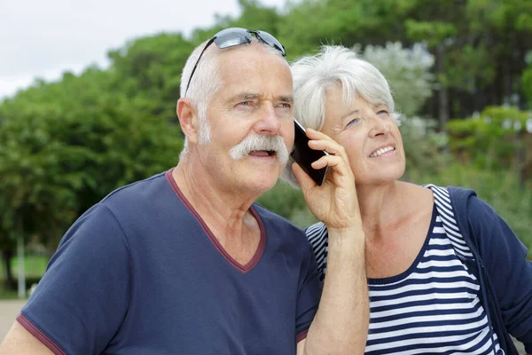 Χαμογελαστό Ζευγάρι Ηλικιωμένων Ακούγοντας Συνομιλία Από Smartphone — Φωτογραφία Αρχείου