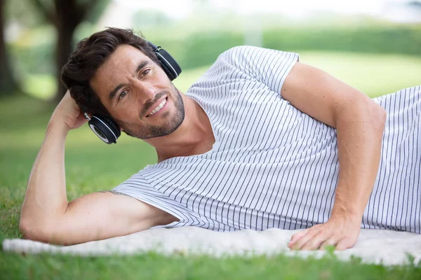 Junger Mann Auf Dem Gras Und Hört Musik — Stockfoto