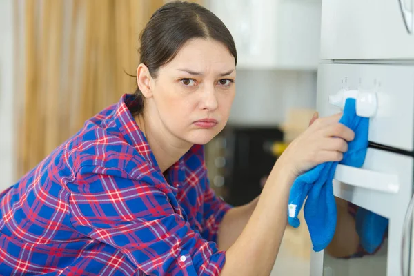 Gelangweilte Junge Frau Putzt Ofen — Stockfoto