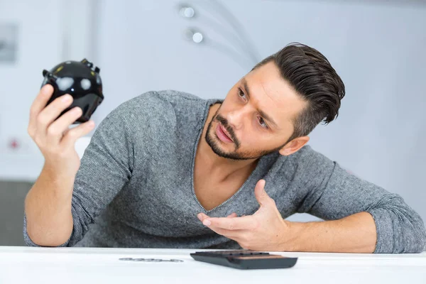 Young Confused Man Holding Piggy Bank — Stock Photo, Image