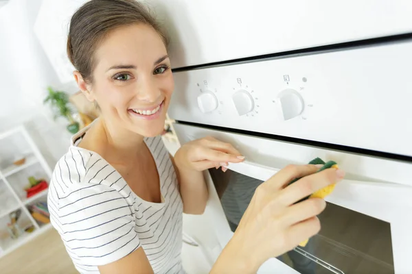 一个快乐的女人正在打扫烤箱 — 图库照片