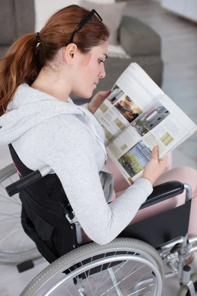 雑誌を持って車椅子に座っている障害者の女性は — ストック写真