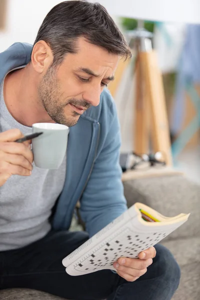 拿着咖啡和拼图书的男人 — 图库照片