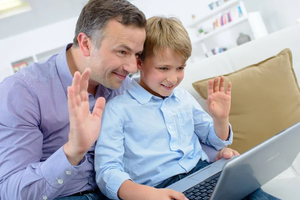 男と子供がコンピュータビデオチャットで手を振る — ストック写真