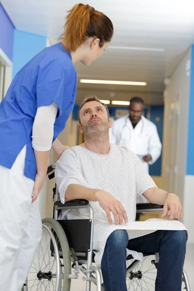 笑顔の麻痺した男を車椅子で支える優しい看護師 — ストック写真