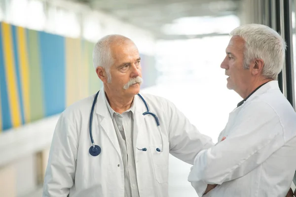 Двоє Старших Лікарів Розмовляють Лікарняному Коридорі — стокове фото