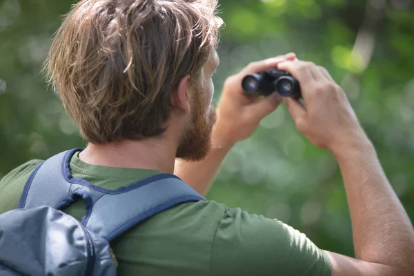 年轻人带着双筒望远镜在湖边观察自然 — 图库照片