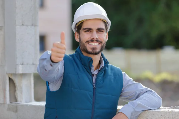 白いヘルメットの笑顔の労働者はジェスチャー親指を作る — ストック写真