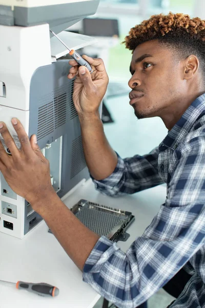 アフリカ人男性が写真複写機を修理し — ストック写真