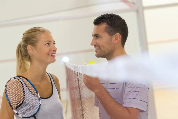 通过羽毛球网交谈的年轻夫妇 — 图库照片