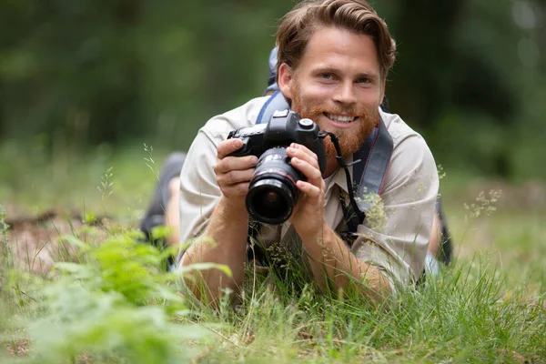 Glimlachende Fotograaf Liggend Het Gras Met Camera — Stockfoto
