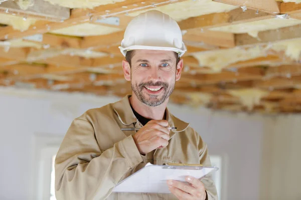 Szczęśliwa Builder Przytrzymanie Schowka Podczas Pracy Pomieszczeniach — Zdjęcie stockowe