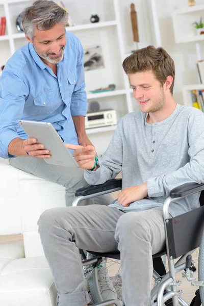 Jovem Cadeira Rodas Apontando Para Tela Tablet Realizada Por Homem — Fotografia de Stock