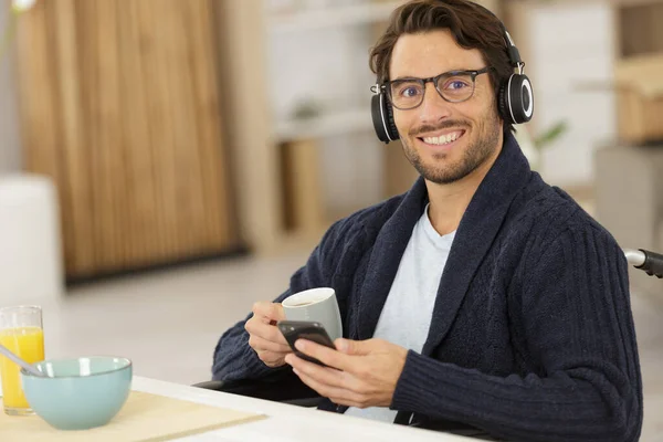 Mężczyzna Uśmiechający Się Telefonem Komórkowym Słuchawkami Podczas Śniadania — Zdjęcie stockowe