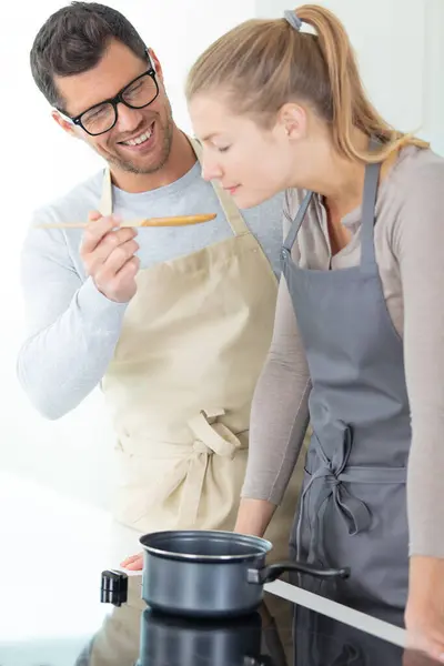 Jovem Mulher Está Degustando Seus Maridos Cozinhar — Fotografia de Stock