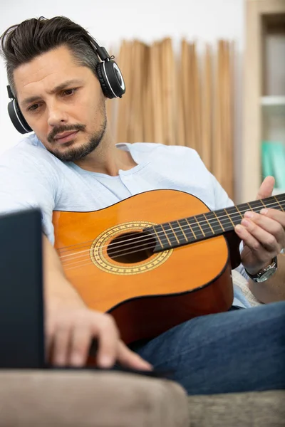 Homem Bonito Tocando Guitarra Casa Enquanto Usando Laptop — Fotografia de Stock