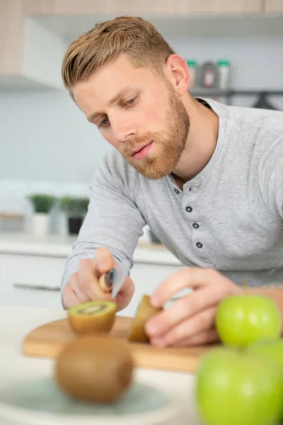Man Snijden Een Kiwi Fruit Helft — Stockfoto