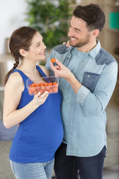 一对夫妇在厨房的内部与一篮子新鲜西红柿 — 图库照片