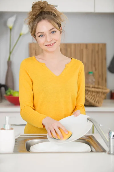年轻女子在厨房里洗碗 — 图库照片