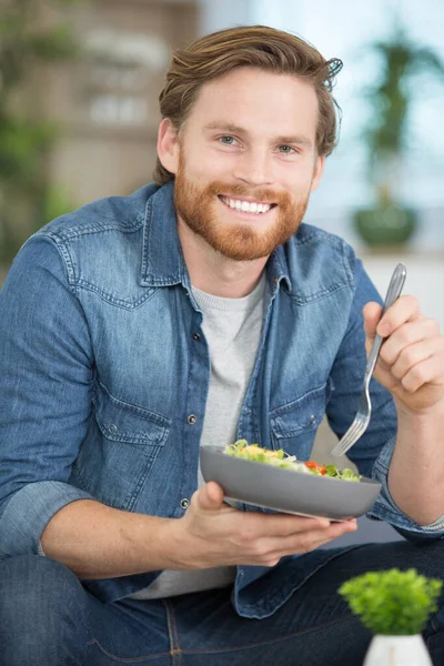 幸せな若い男がサラダを食べて — ストック写真