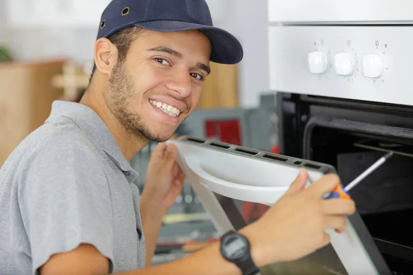 電気オーブンに合う若いサービスマンの肖像画 — ストック写真