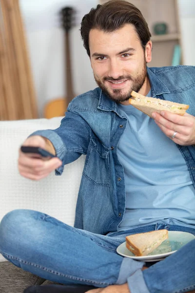 Мужчина Меняет Телеканал Время Еды Бутерброда — стоковое фото